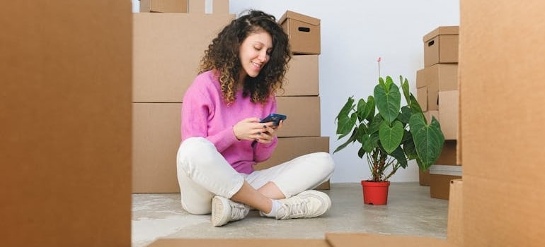 A woman in pink sweater searching for signs of a moving scam on smartphone