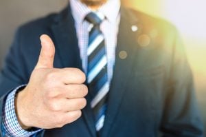 Person in a suit holding a thumbs up