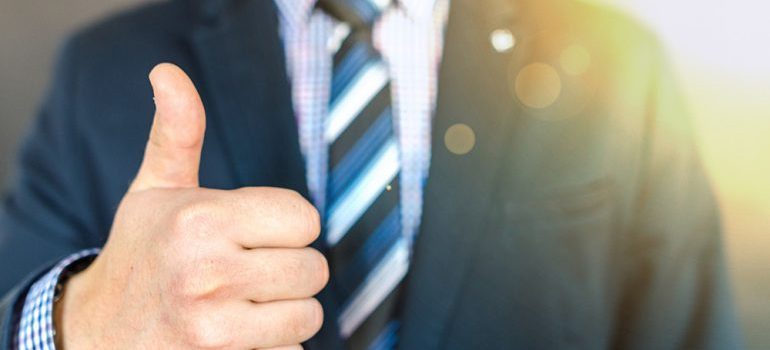 Person in a suit holding a thumbs up