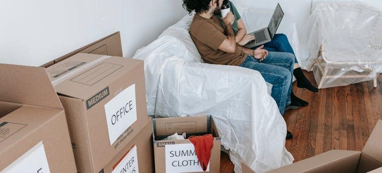 A couple sitting amid boxes explores things they shuld do right after you move