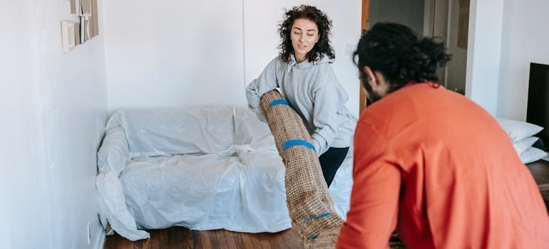 A couple carrying a rolled carpet