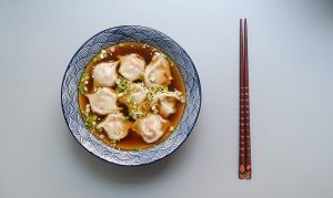 A bowl of chinese soup with a set of chopsticks