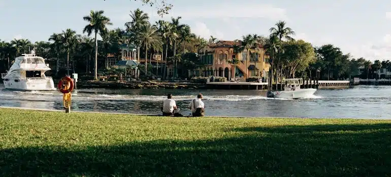 People sitting on grass near boats and palm trees after moving to Fort Lauderdale