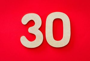 A white number thirty on a red background