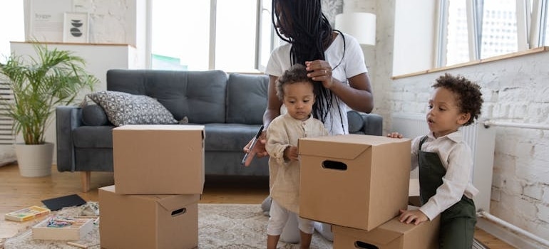 A mother packing boxes with two kids