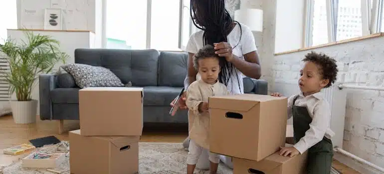 A mother packing boxes with two kids