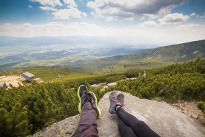 Two people sitting on the rock and watching skyline.