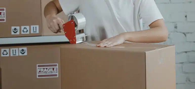 A person taping a cardboard box for storage