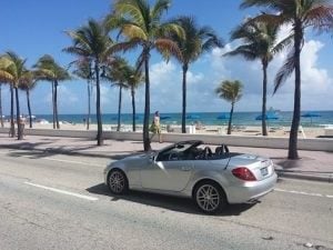 Cabriolet next to a beach and palm trees 