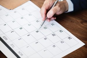 Person pointing at a calendar.