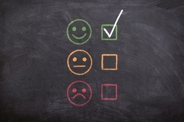 A black board with drawn smileys in different colors.