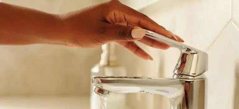 Close-up of a woman’s hand turning on a bathroom faucet