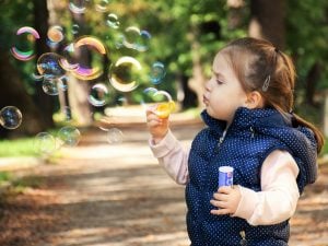 a young girl blowing soap bubbles