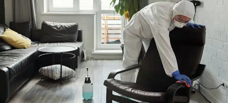A person in PPE wiping the sofa chair