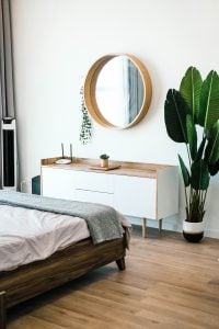 a bedroom with a plant, bed and a mirror on the wall