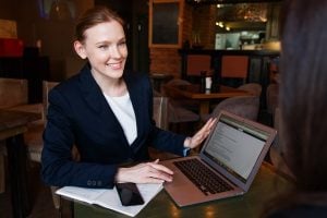 A woman smiling and holding a laptop.