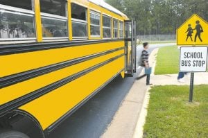 A girl coming off of a school bus.