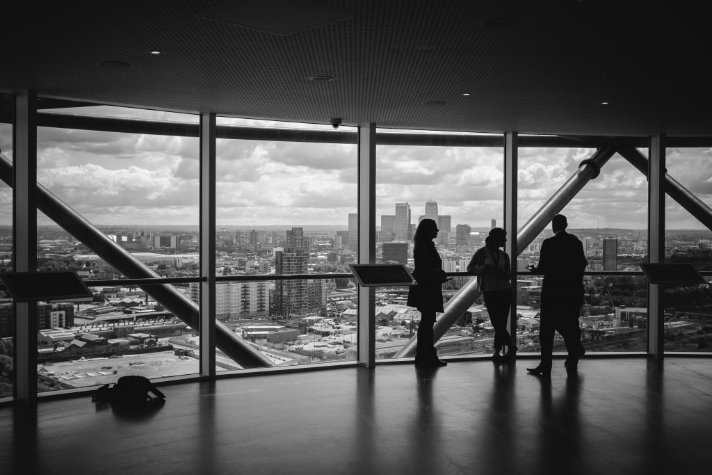 people standing in next to large windows