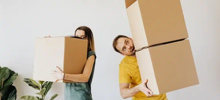 A couple carrying boxes with belongings