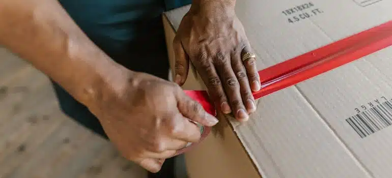 Close-Up Shot of a Person Putting Tape on a Cardboard Box