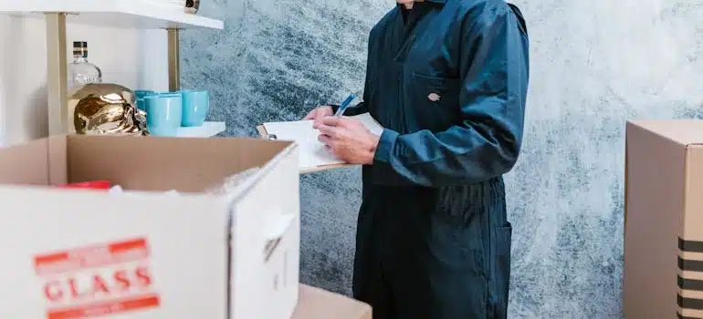 A mover inventories glass and china before packing into labeled boxes.