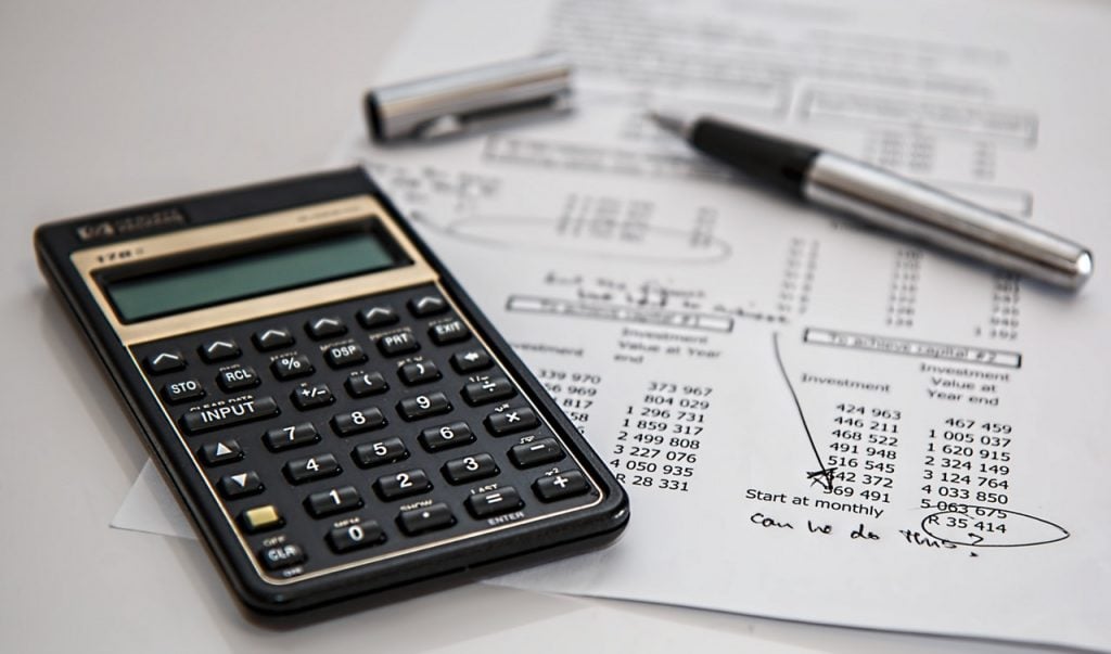 Black calculator and a pen on printed paper