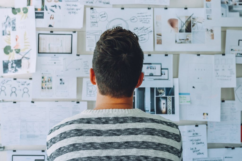 Man looking at a wall filled with papers