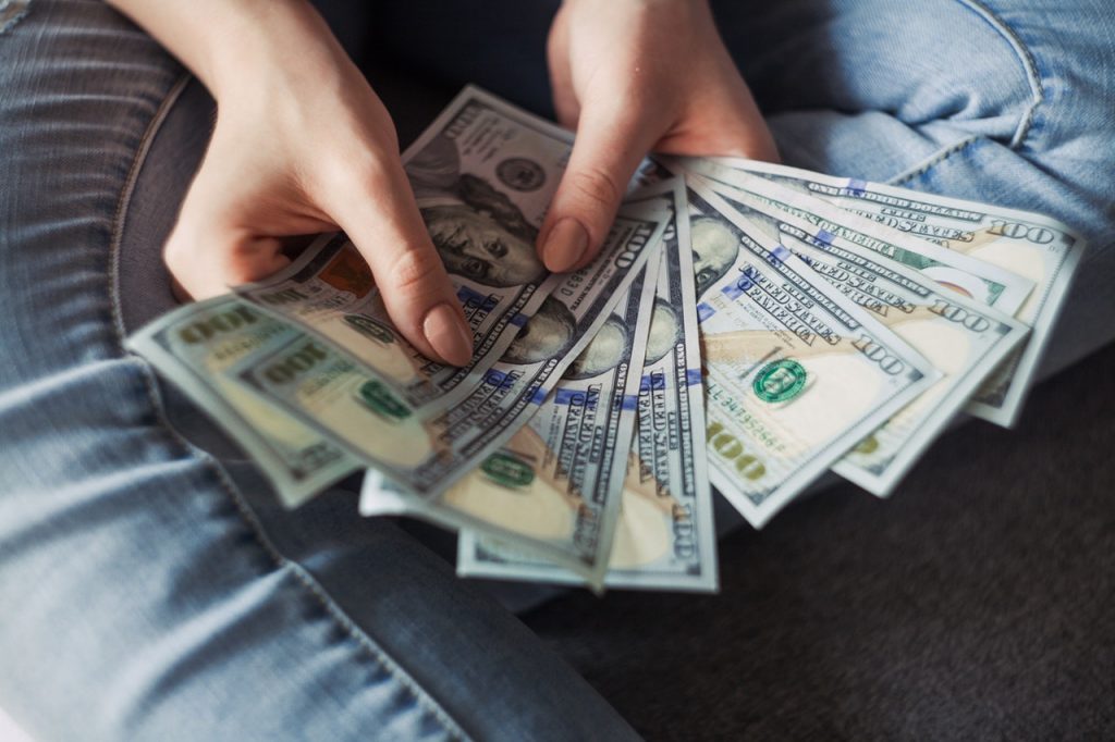 Person holding 100 US dollar banknotes