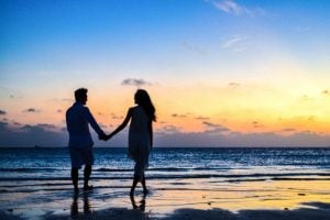 Couple holding hands and walking on seashore