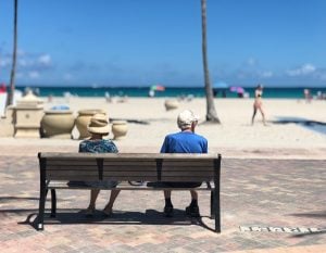 senior couple sitting on a bench near the beach