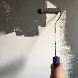 person painting a grey wall