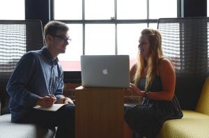 a man and a woman in the office looking at a laptop