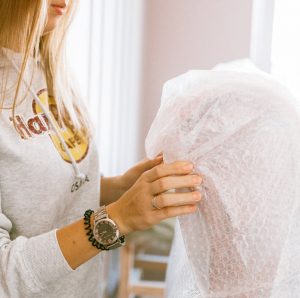 moving during a rainstorm - a woman placing bubble wrap over the arm chair