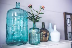 handle sentimental clutter by reusing it in your daily life. five vases on a shelf and one contains flowers