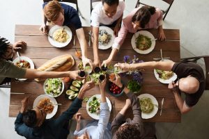 group of people making toast over a dinning room table