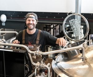 man standing in a brewery next to large machines