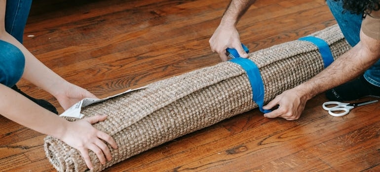 Man Putting Blue tape On A Rolled Carpet