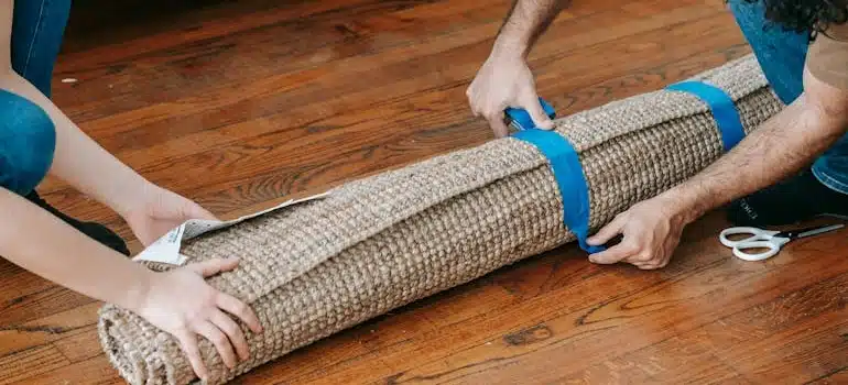 Man Putting Blue tape On A Rolled Carpet