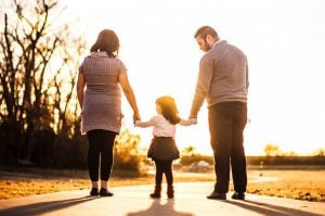 parents walking, holding their child`s arm during the day 