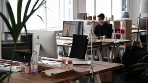 a view of the office with desks, laptops and one employee