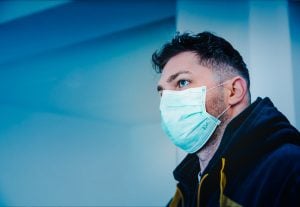 a man in a black and yellow hoodie wearing a face mask