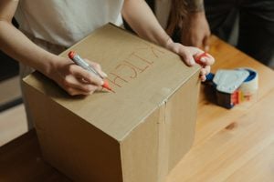 A woman writing kitchen on a moving box with a red pen