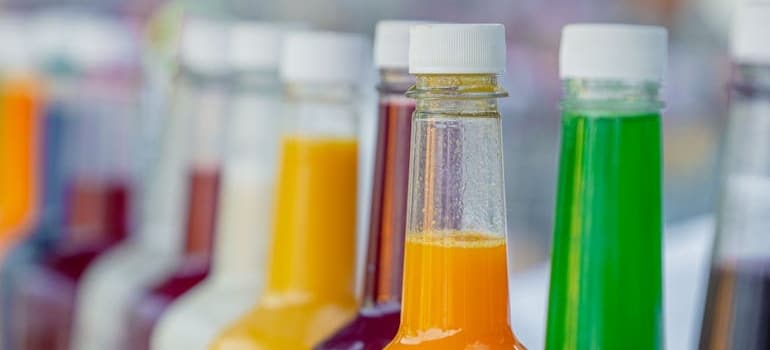 A row of bottles with liquids in a fridge