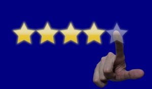 A finger pointing to a five star review on a blue surface