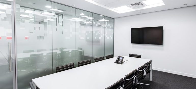 a photo of an office after moving offices in the Miami Dade area, a long desk with chairs, and a TV on the wall
