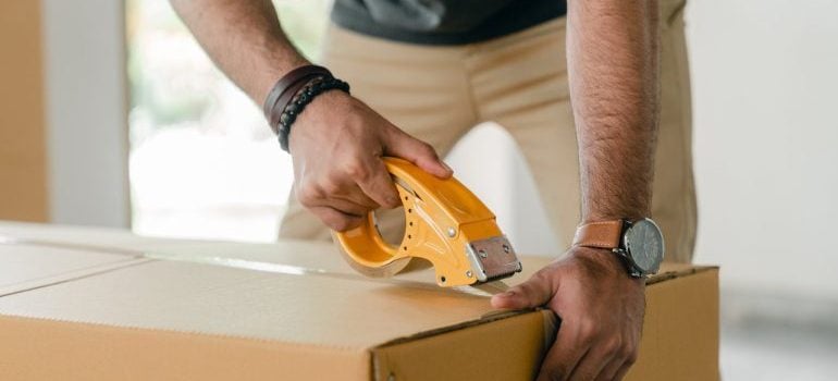 a professional mover taping a moving box 