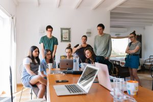 a group of employees gathered around a laptop, discussing movign offices in the Miami Dade area