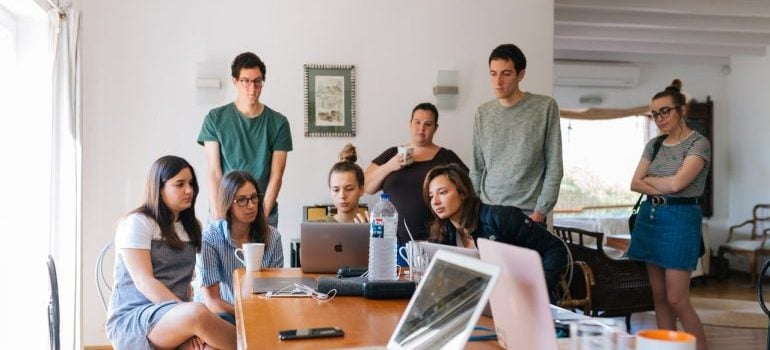 a group of employees gathered around a laptop, discussing movign offices in the Miami Dade area