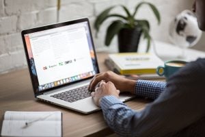 A man looking at his laptop with crossed hands, reading about the best ways for moving your offices