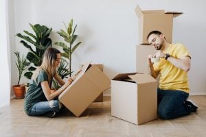 a woman and a man labeling two moving boxes on the floor